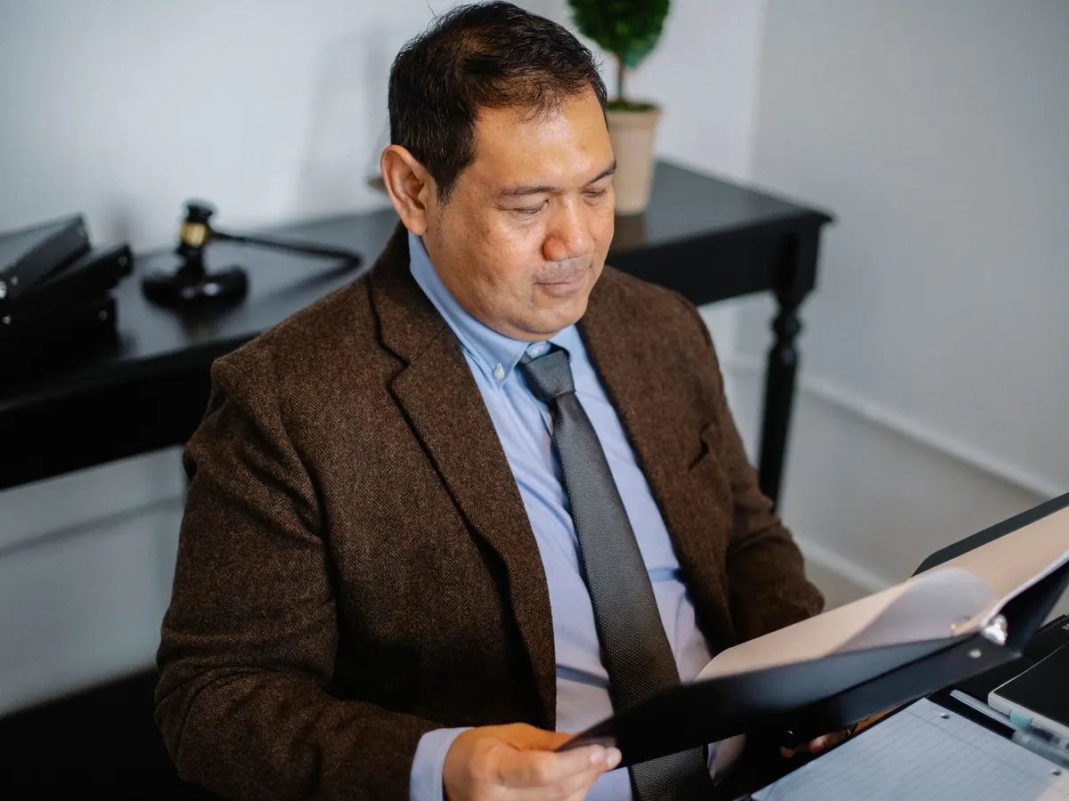 Un profesional de traje revisa un informe dentro de una carpeta en su oficina