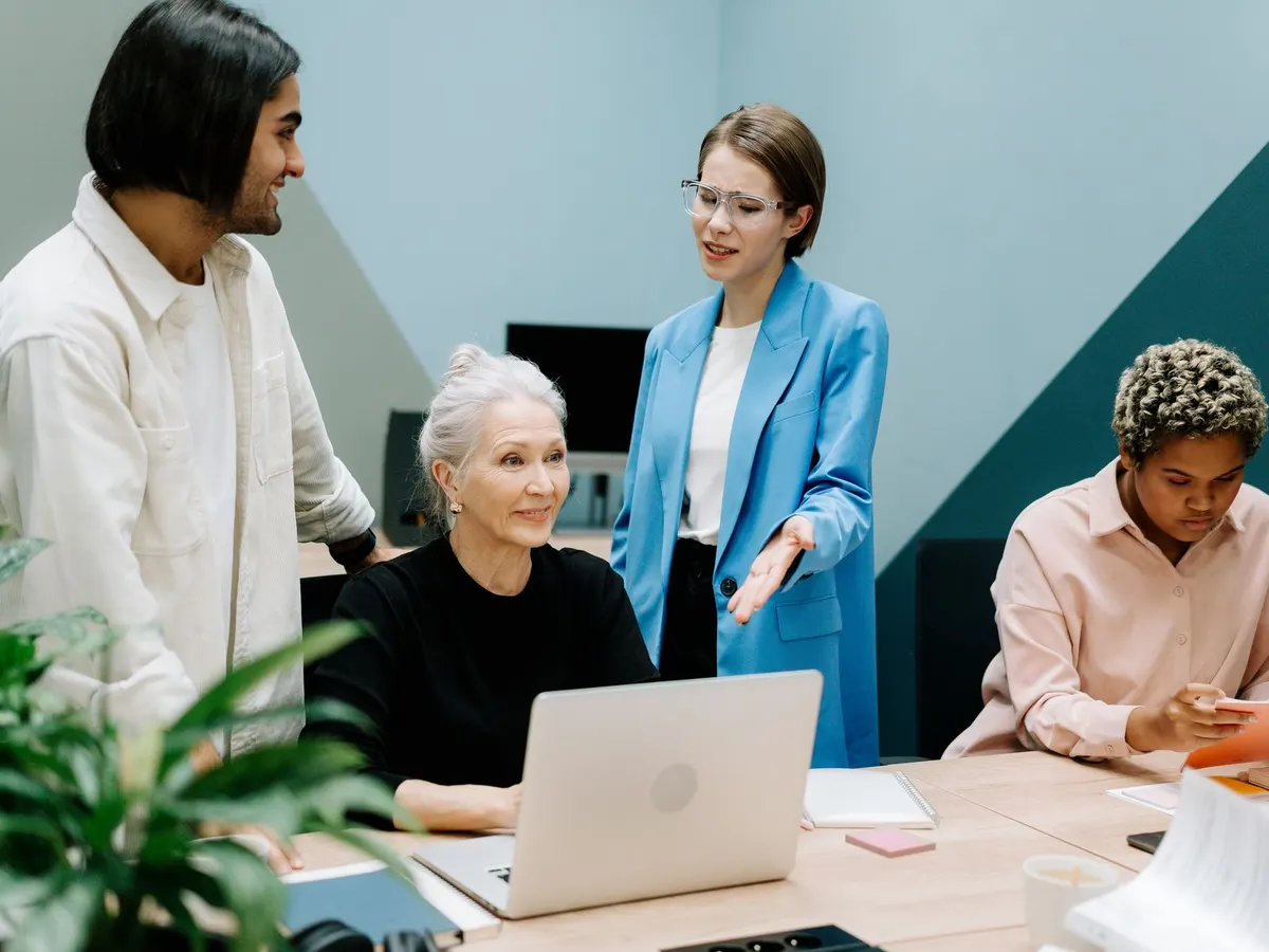 Un equipo de oficina revisa información en una laptop alrededor de una mesa de trabajo